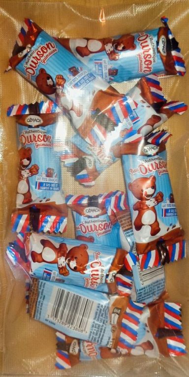 L’Authentique Petit Ourson Guimauve Barres de chocolat emballées, avec un motif rouge, blanc et bleu, disposées dans un plat.